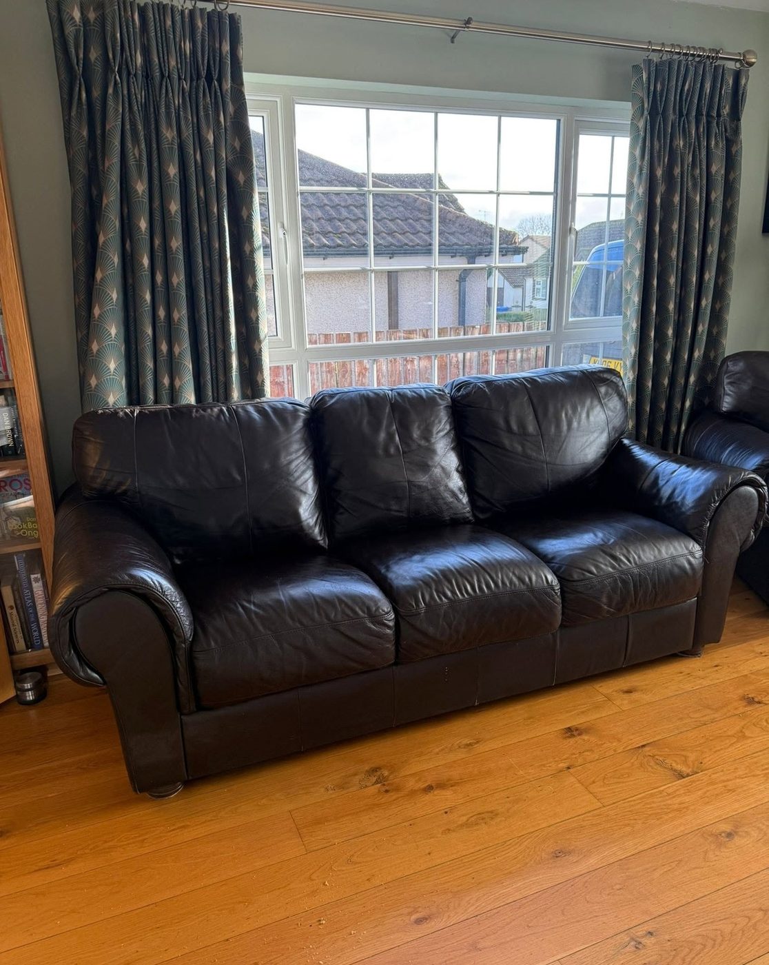The black leather sofa after repair, in a living room by the window