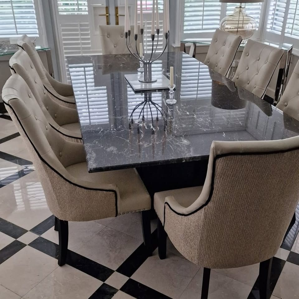 Dining table with upholstered chairs, candelabras and candleholders in a room with shuttered windows