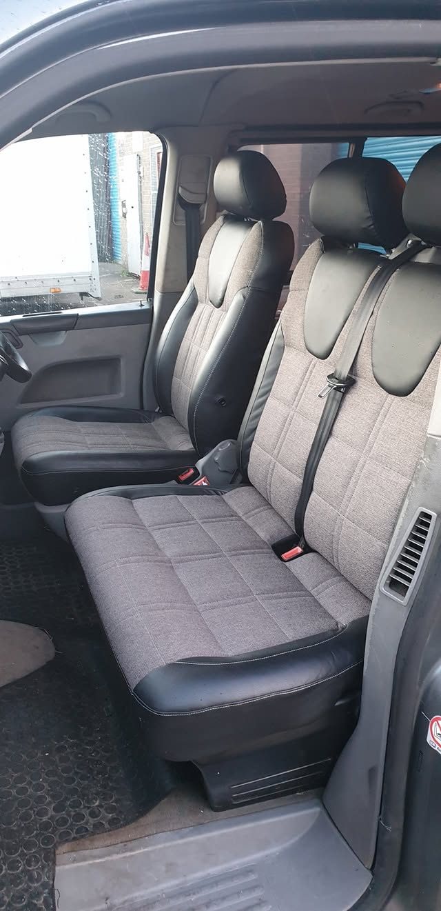 Open van cabin with grey fabric front seats and bench seat, viewed through the side door